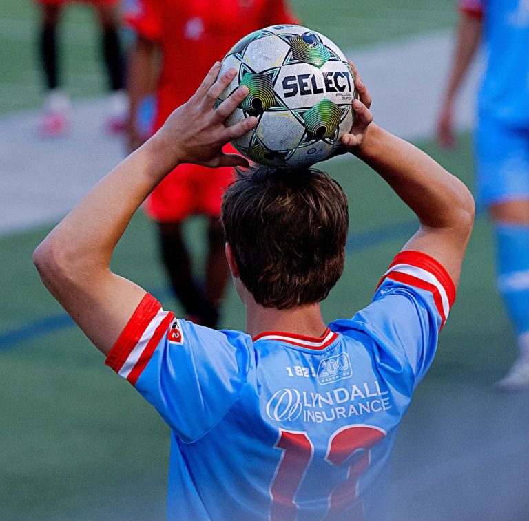 Akron City player holding soccer ball above his head for a throw-in